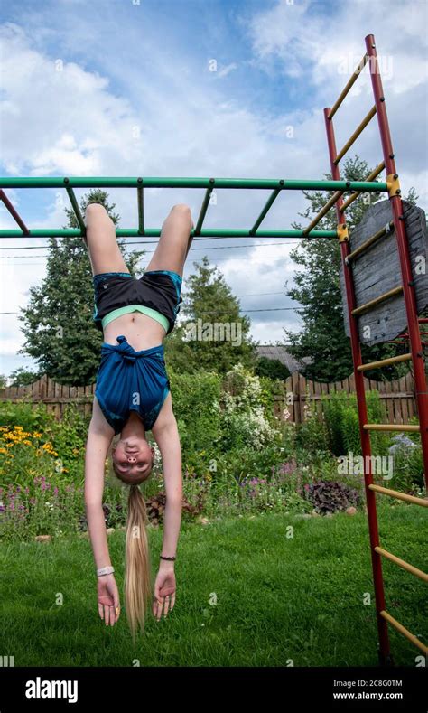 A Girl Is Hanging Upside Down On A Horizontal Bar Stock Photo Alamy
