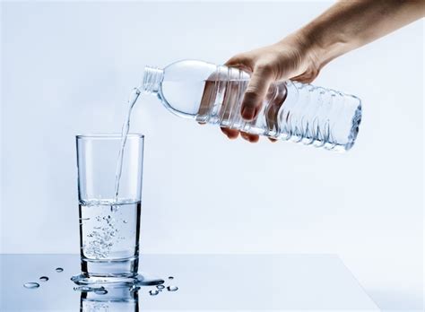 Premium Photo Hand Pouring Fresh Pure Water From Bottle Into A Glass