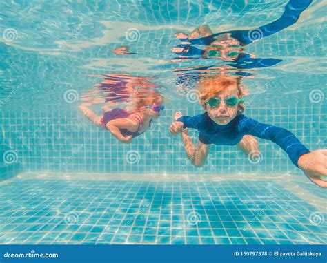 Kids Having Fun Playing Underwater In Swimming Pool On Summer Vacation