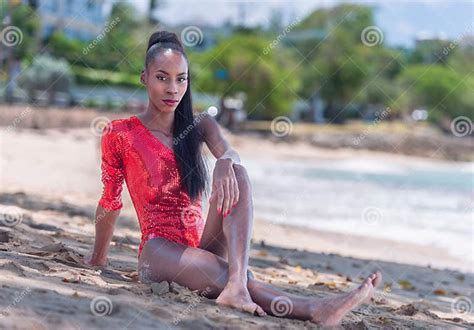 Portrait Of Beautiful Caribbean Adult Teen In Barbados Wearing Red Bikini And Sitting On A