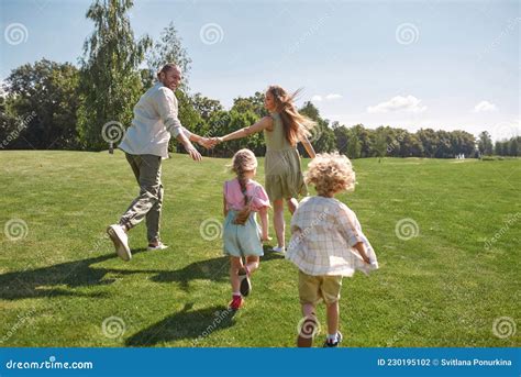 Padres Alegres Cogiendo La Mano Corriendo De Su Pequeño Niño Y Niña