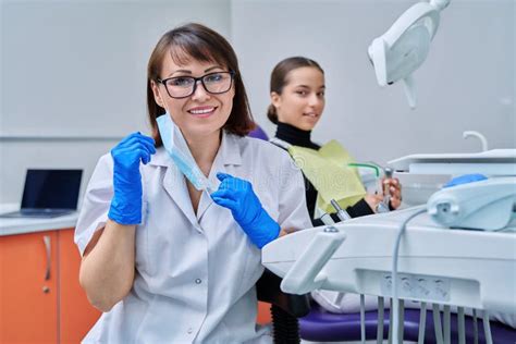 Portrait Of Female Dentist With Girl Patient Sitting In Dental Chair