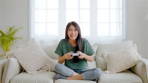 Beautiful Young Asian Woman Sitting In Living Room Sofa Holding