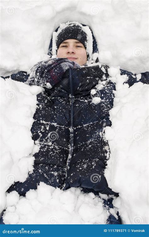 Teenager Boy Lies In Deep Snow Under A Heavy Snowfall Stock Image