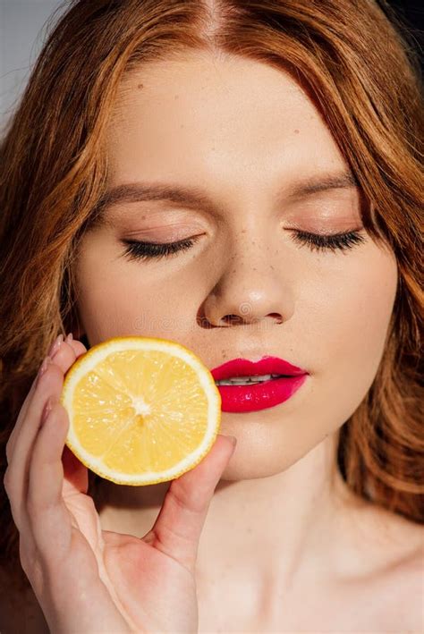 Beautiful Sensual Redhead Girl With Red Lips And Eyes Closed Posing With Cut Lemon Stock Image