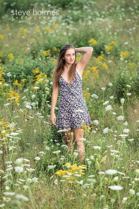 Teenaged Girl Brushes Back Hair As She Walks Through Field Of Flowers