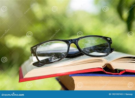 Open Book And Eyeglasses On A Wooden Table In A Garden Sunny Summer