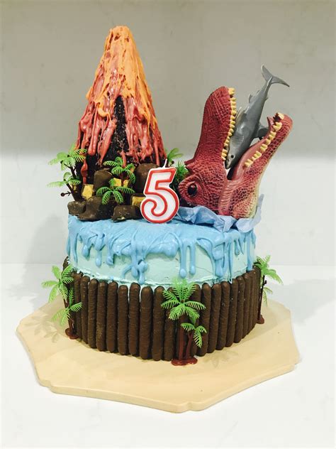There Is A Cake That Looks Like It Has Dinosaurs On Top And The Number Five