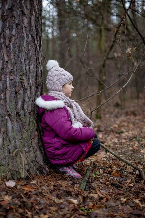 Little Girl Sitting Near A Tree In An Autumn Forest Stock Photo Image