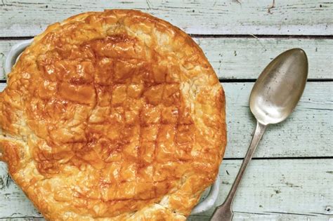 A Pie Sitting On Top Of A Wooden Table Next To A Fork And Spoons