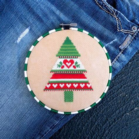 a cross stitch christmas tree ornament on jeans