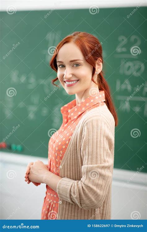 Red Haired Math Teacher Standing Near Blackboard In Classroom Stock