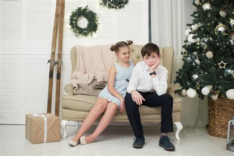 den torterade bror och syster sitter på soffan vid julgranen fotografering för bildbyråer bild