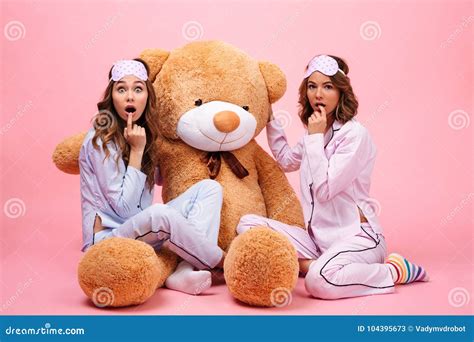 Two Excited Girls In Pajamas Sitting With A Teddy Bear Stock Image