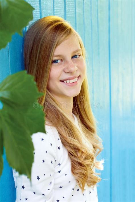 Portrait Of Pretty Teen Girl On Blue Wooden Wall Background Stock Photo