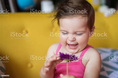 Baby Girl Smelling Flower And Smiling Stock Photo Download Image Now