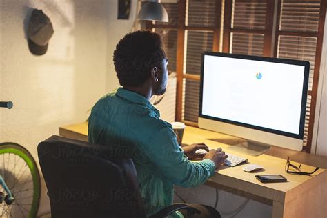 Creative Black Man Using Computer At Late Afternoon On His Office By