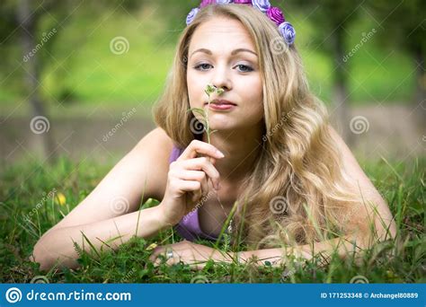 Beautiful Blonde Girl Lying On The Grass And Smelling A Flower Stock Photo Image Of Green