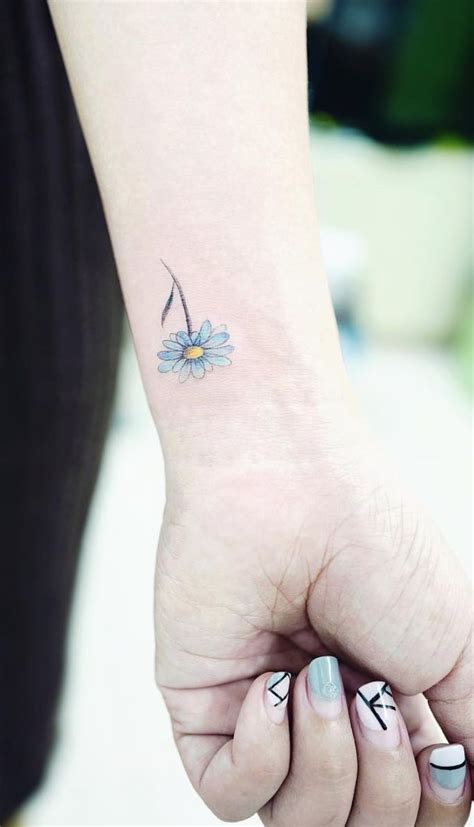 A Small Blue Flower Tattoo On The Left Wrist And Right Hand With An