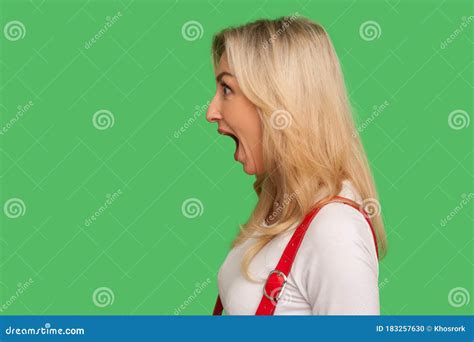 wow unbelievable side view of astonished adult blond woman standing with wide open mouth and