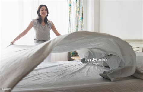 Usa New Jersey Young Woman Spreading Sheet On Bed Photo Getty Images