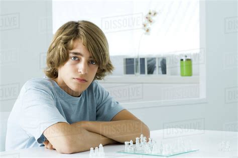 Teen Boy Sitting At Table Playing Chess Looking At Camera Stock