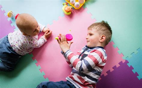 Cute Little Children Playing While Sitting On Carpet Stock Photo