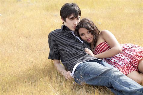 Young Teen Couple Reclining In Yellow Grass Royalty Free Stock Images