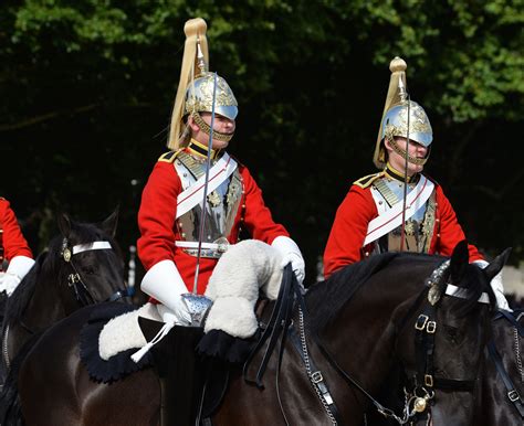 Two Men In Red Uniforms Riding On Horses