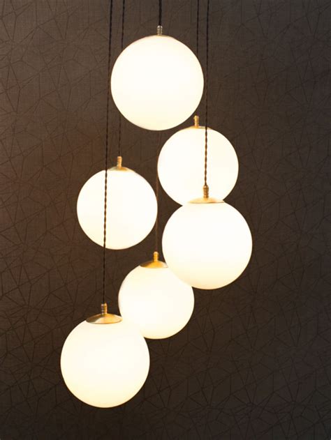 A Bespoke Cluster Of Six Opal Globes With A Subtle Brass Finish Suspended From A Ceiling Plate