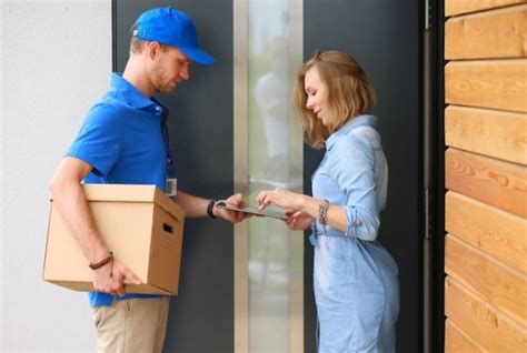 Smiling Delivery Man In Blue Uniform Delivering Parcel Box To Recipient