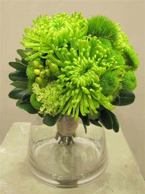 A Vase Filled With Green Flowers On Top Of A Table