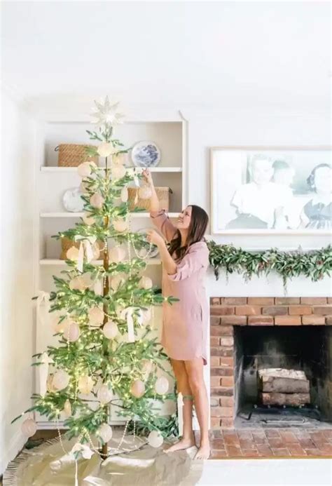 A Woman Decorating A Christmas Tree In Her Living Room With Greenery On