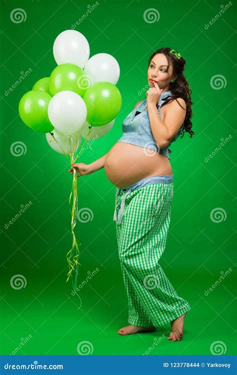 Pregnant Woman With Balloons On A Green Background He Looks At His