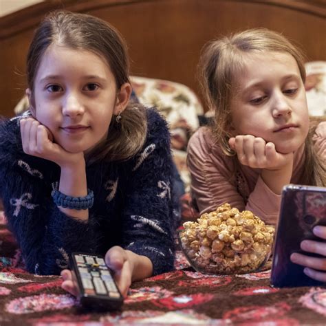 Two Happy Girls Watching Tv Or Movie With Popcorn A Horizontal Photo Of Two License
