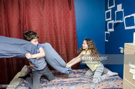 Brother And Sister Having A Pillow Fight In Bed Photos And Premium High