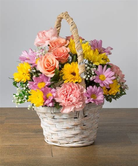 A Basket Filled With Flowers Sitting On Top Of A Wooden Table