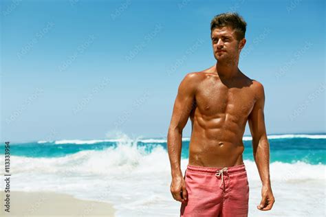 sexy man on beach in summer handsome male with fit body healthy skin sun tan tanning near sea