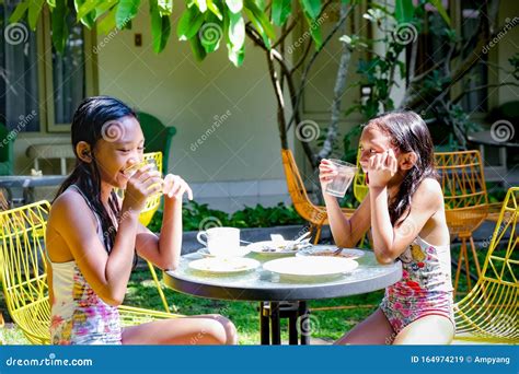 Two Asian Girls In Swimsuit Having Some Meals And Fun Together After Swimming Activities Stock