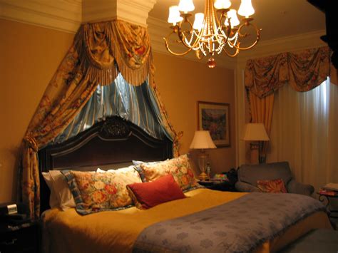 a large bed sitting under a chandelier in a bedroom next to two lamps