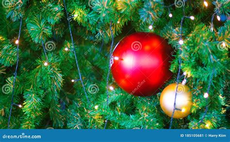 Red Bauble Hanging From A Decorated Of Spruce Christmas Tree With Light