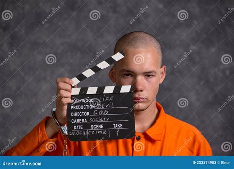 Young Male Prisoner Holding Clapper Board Isolated On Grey Stock Image