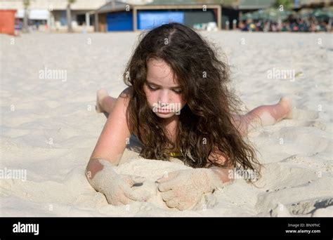 Girl Lying On Her Front On The Beach Playing By Herself In The Sand Stock Photo Alamy