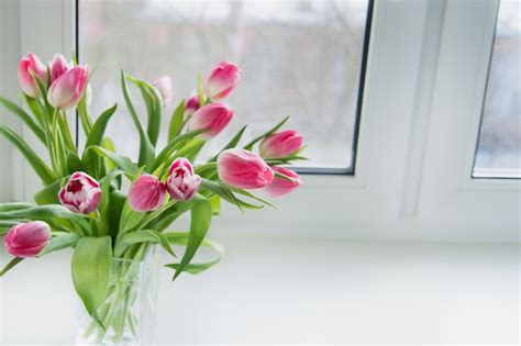 Premium Photo A Bouquet Of Pink Tulips In A Glass Jar Is On The