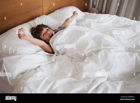 Boy Yawning While Stretching Arms In Bed Stock Photo Alamy