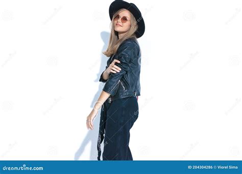 Side View Of Smiling Young Woman Holding Arm In Fashion Pose Stock