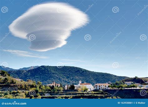Large Lenticular Cloud Hovers Over A Hillside Spanish Village Stock