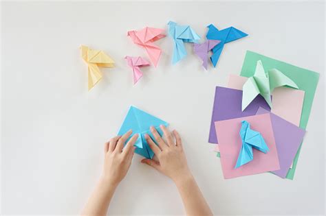 Childrens Hands Do Origami From Colored Paper On White Background