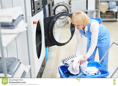 The Worker Loads The Laundry Clothing Into The Washing Machine Stock