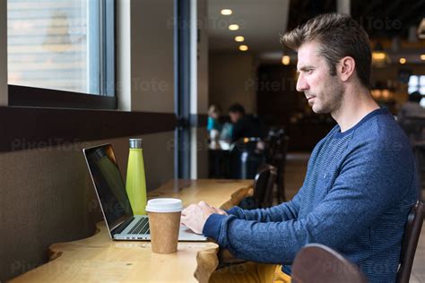 Man Working Remotely On A Laptop From A Coffee Shop Stock Photo